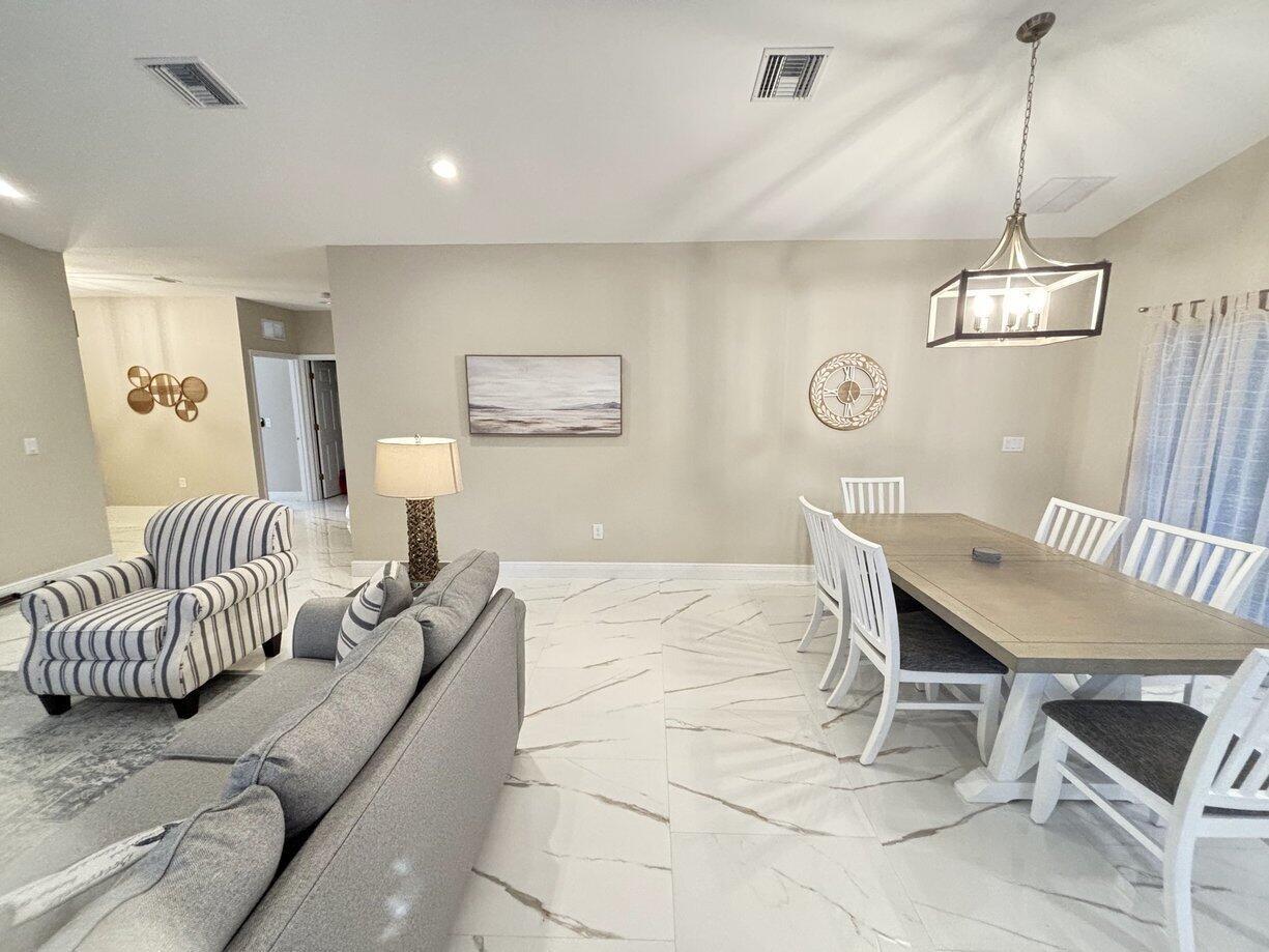 A living and dining room area features white marble-look tile flooring and neutral walls — 1330 28th Avenue, Vero Beach FL 32960, VERO BEACH, FL
