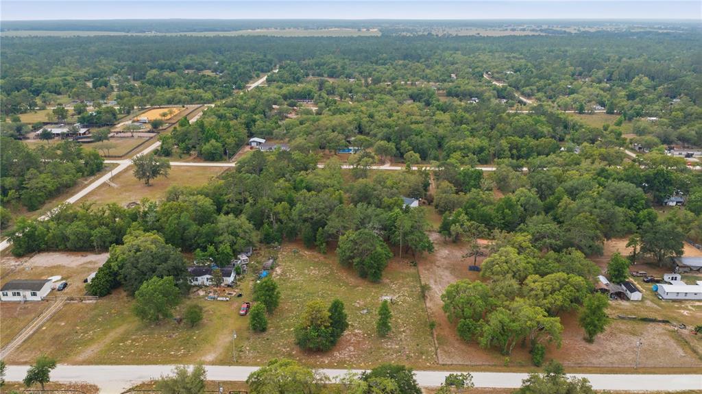 An aerial view shows a rural residential area with scattered houses, trees, and dirt roads — TBD SE 66 STREET, MORRISTON, FL
