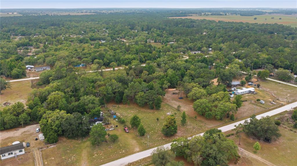 An aerial view shows rural residential properties with houses, trees, and dirt roads — TBD SE 66 STREET, MORRISTON, FL