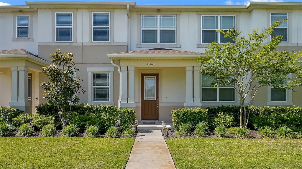 The exterior of a two-story townhouse features a brown front door and a concrete walkway — 11761 TIDAL ALLEY, ORLANDO, FL