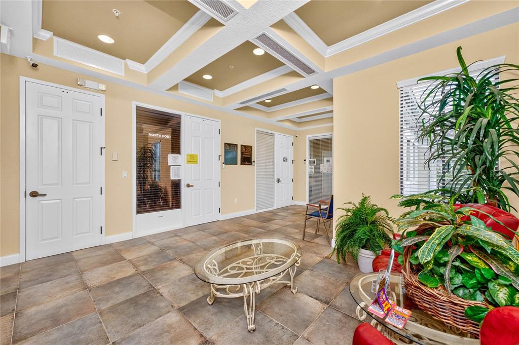 A lobby area features tile flooring, a glass coffee table, and several potted indoor plants — 5900 PAN AMERICAN BOULEVARD, NORTH PORT, FL