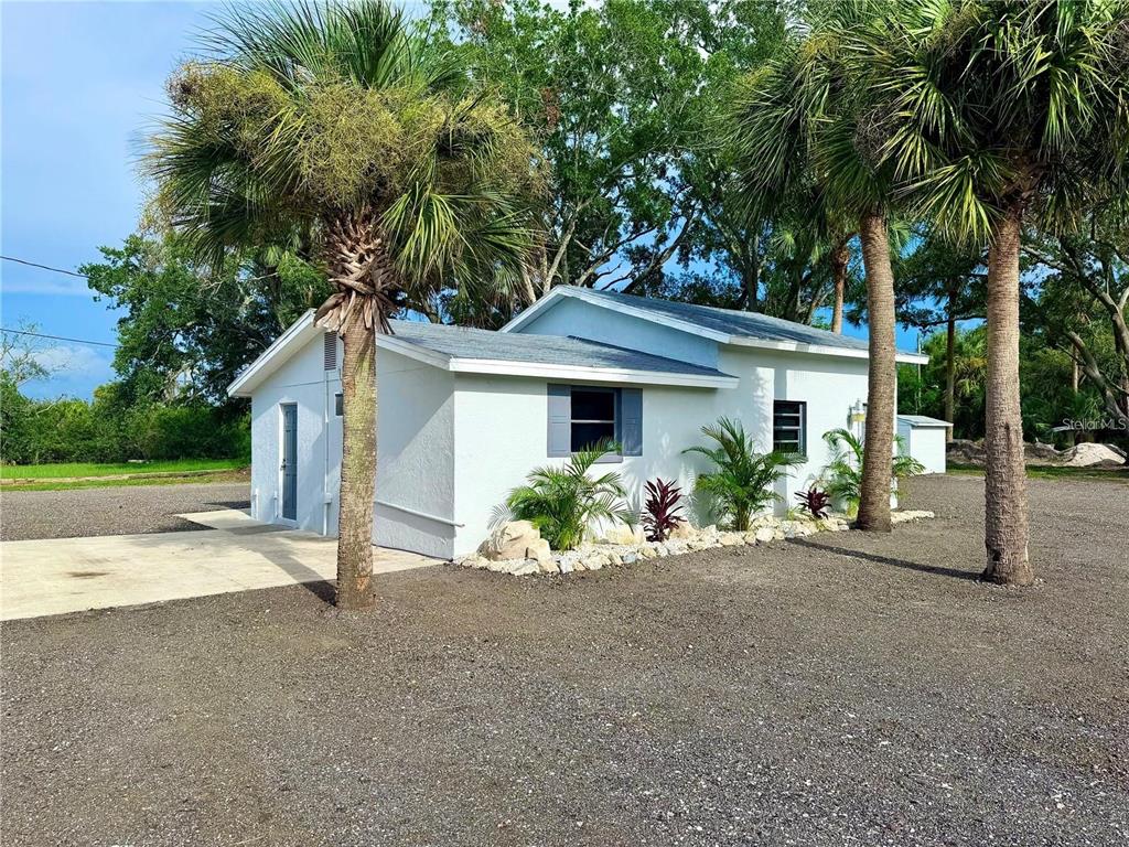 A white, single-story house with a gravel yard and palm trees under a blue sky — 1322 N PINELLAS AVENUE, TARPON SPRINGS, FL