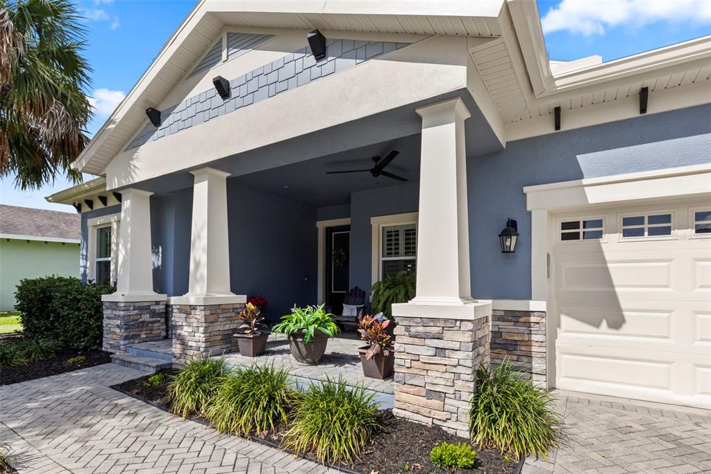 The exterior of a blue house features a covered porch with stone-based columns — 5805 WATERCOLOR DRIVE, LITHIA, FL