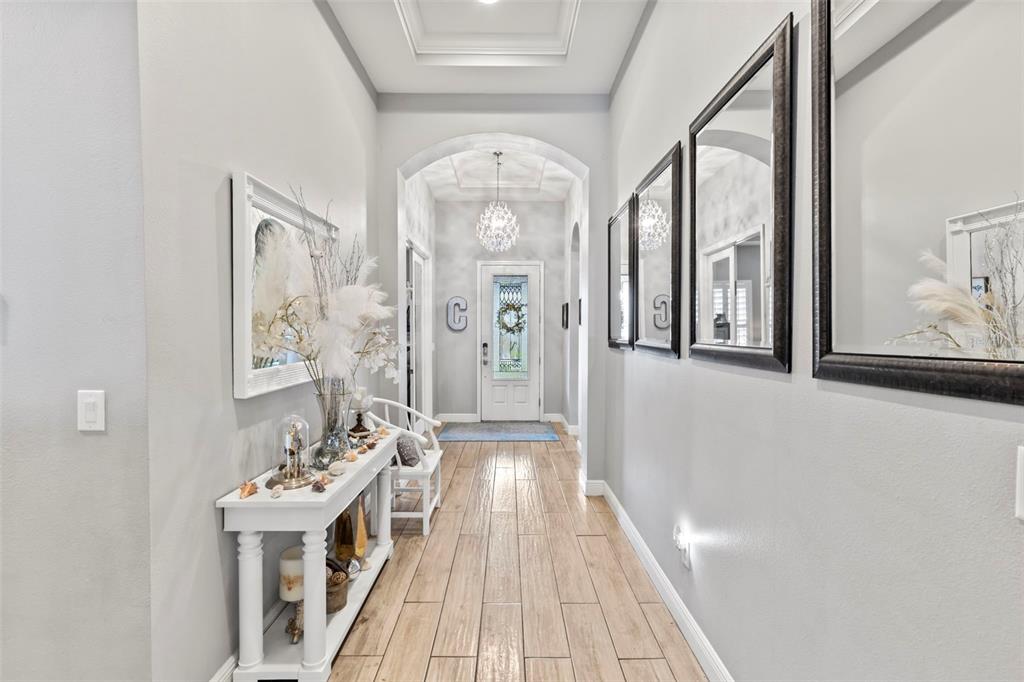A bright hallway features light wood-look tile flooring, a white console table, and wall mirrors — 5805 WATERCOLOR DRIVE, LITHIA, FL