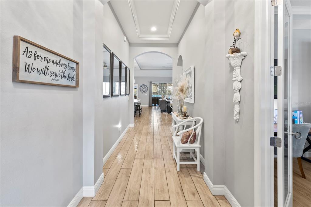 A hallway with wood-look tile flooring leads toward an open living area with glass doors — 5805 WATERCOLOR DRIVE, LITHIA, FL