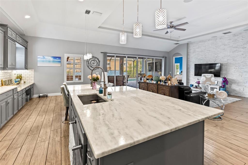 A kitchen with a large marble-topped island overlooks an open-concept living area with tile flooring — 5805 WATERCOLOR DRIVE, LITHIA, FL