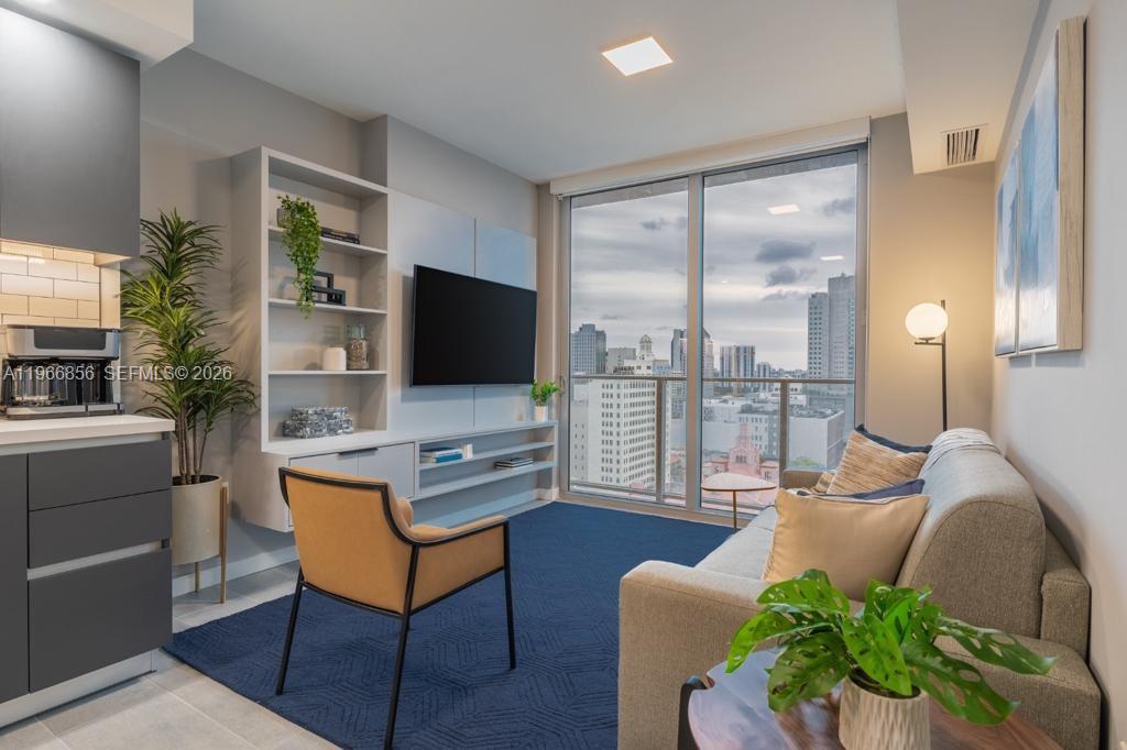 A modern living room features a blue area rug, a sofa, and a city view — 227 NE 2nd St # 1905, Miami FL 33132, MIAMI, FL