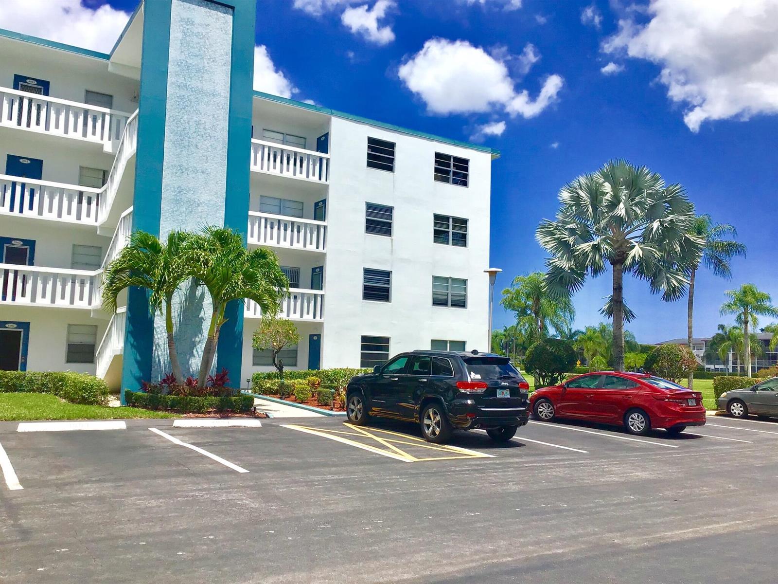 A multi-story white apartment building with teal accents sits behind a parking lot with cars — 4004 Exeter A, Boca Raton FL 33434, BOCA RATON, FL