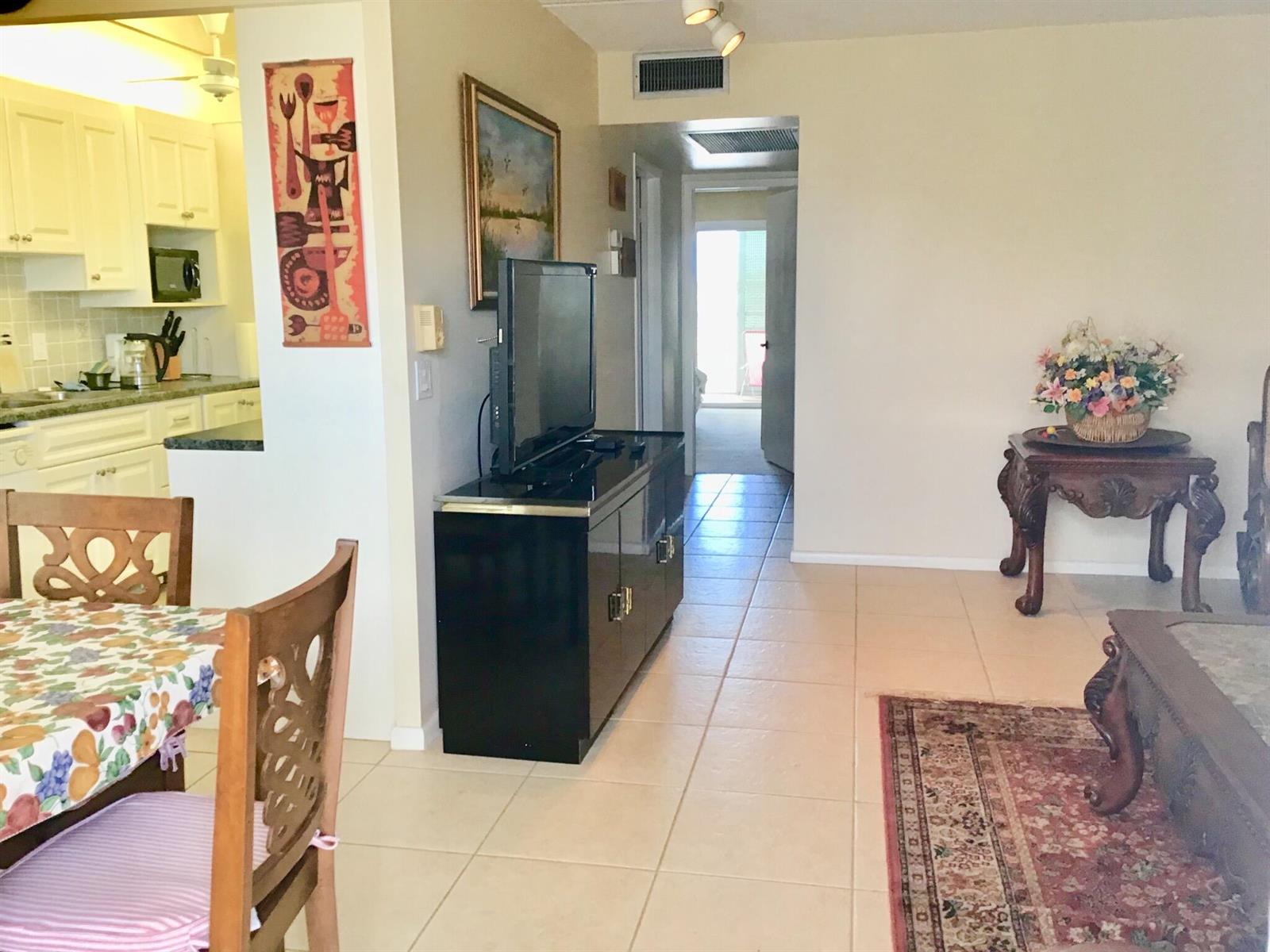 A living room with tile floors, a black media console, and an adjacent kitchen — 4004 Exeter A, Boca Raton FL 33434, BOCA RATON, FL