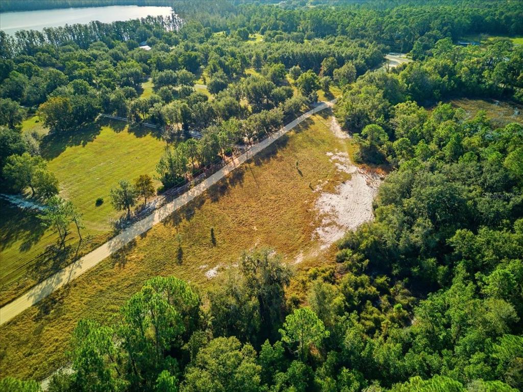 An aerial view shows a dirt road cutting through a grassy, partially wooded rural lot — LAKE ERIE RD, GROVELAND, FL