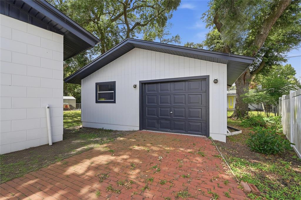 A detached garage with white siding, a dark trim, and a red brick driveway — 1946 STRATHAVEN ROAD, WINTER PARK, FL