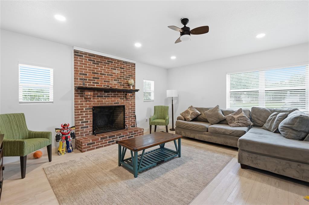 A living room features a brick fireplace, a sectional sofa, and a wooden coffee table — 1946 STRATHAVEN ROAD, WINTER PARK, FL