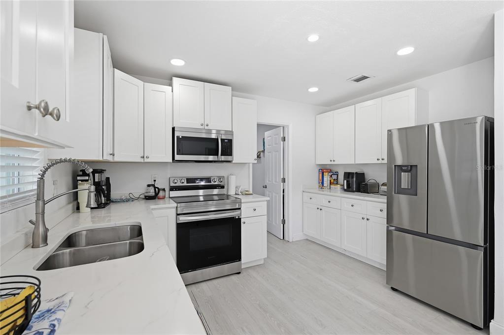 A kitchen features white cabinets, stainless steel appliances, and white countertops with a double sink — 1946 STRATHAVEN ROAD, WINTER PARK, FL