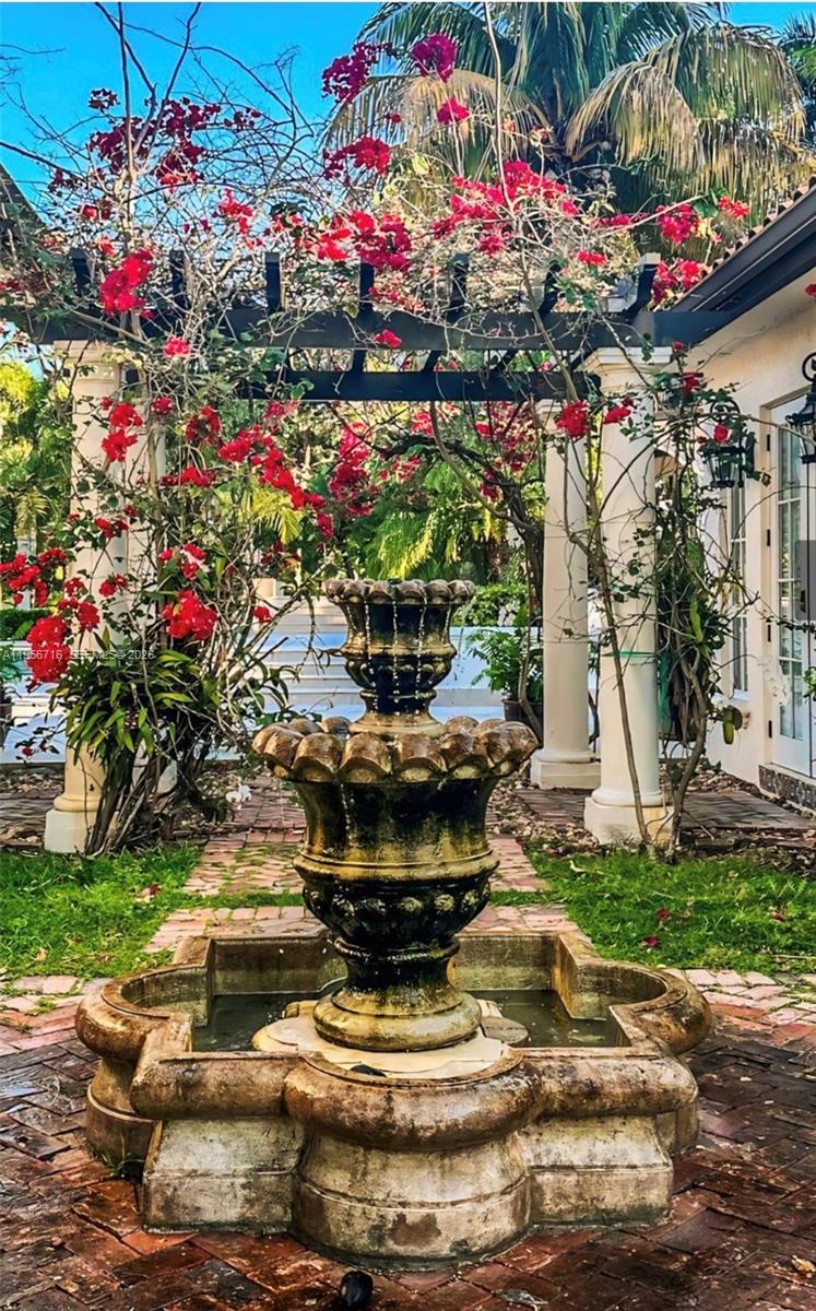 A tiered stone fountain stands in a brick courtyard beneath a bougainvillea-covered wooden pergola — 14949 SW 184th Ave, Miami FL 33196, MIAMI, FL