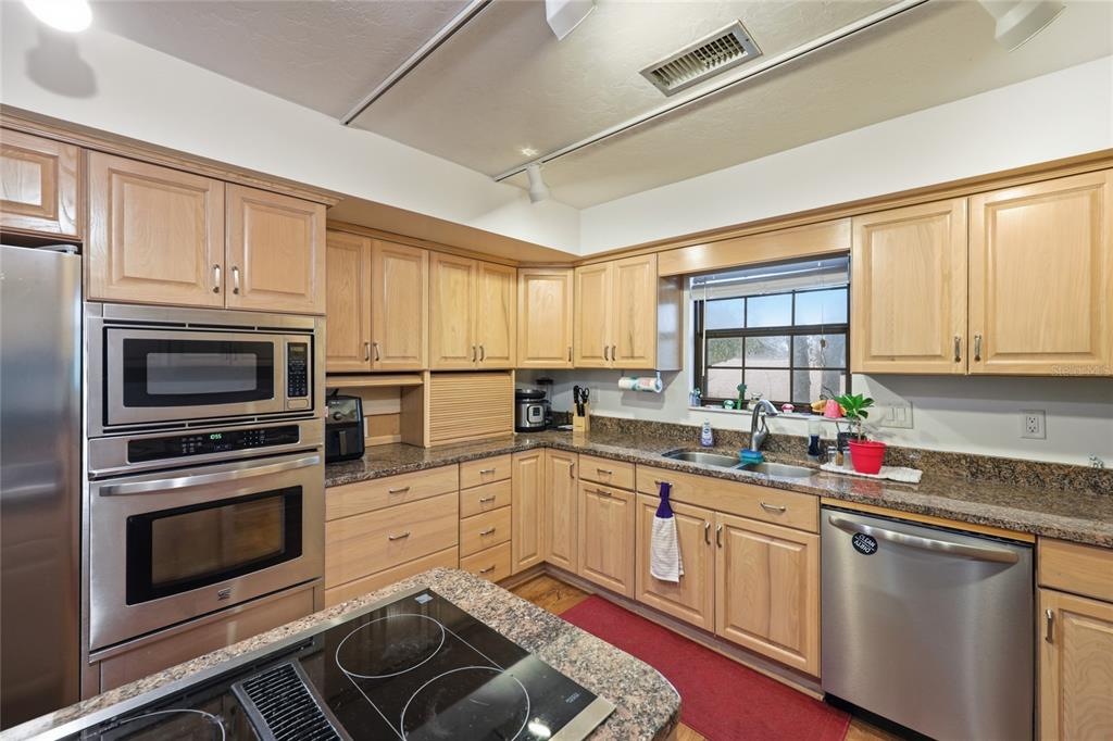 A kitchen features light wood cabinets, granite countertops, stainless steel appliances, and a central island — 18784 NW 230TH STREET, HIGH SPRINGS, FL