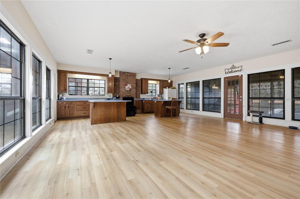 A spacious kitchen and living area features light wood flooring, wood cabinetry, and large windows — 18784 NW 230TH STREET, HIGH SPRINGS, FL