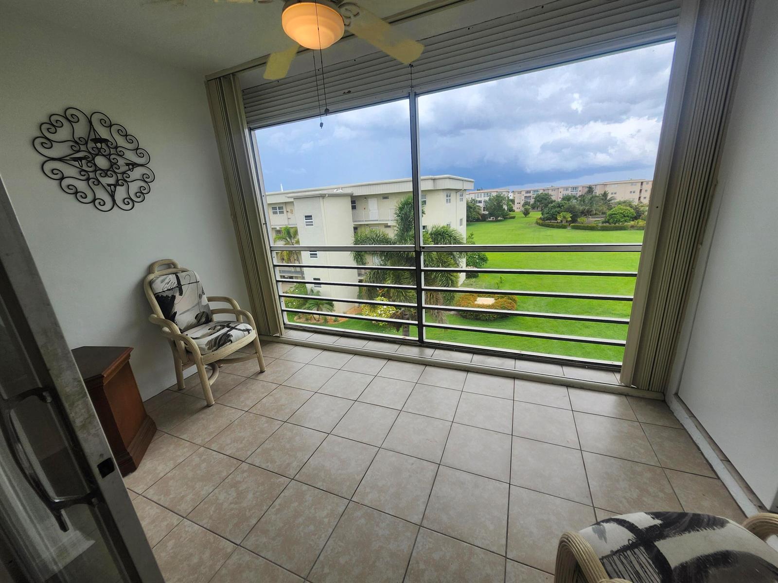 A tiled balcony features a ceiling fan, a wicker chair, and a view of grounds — 2600 NE 1st Lane # 402, Boynton Beach FL 33435, BOYNTON BEACH, FL