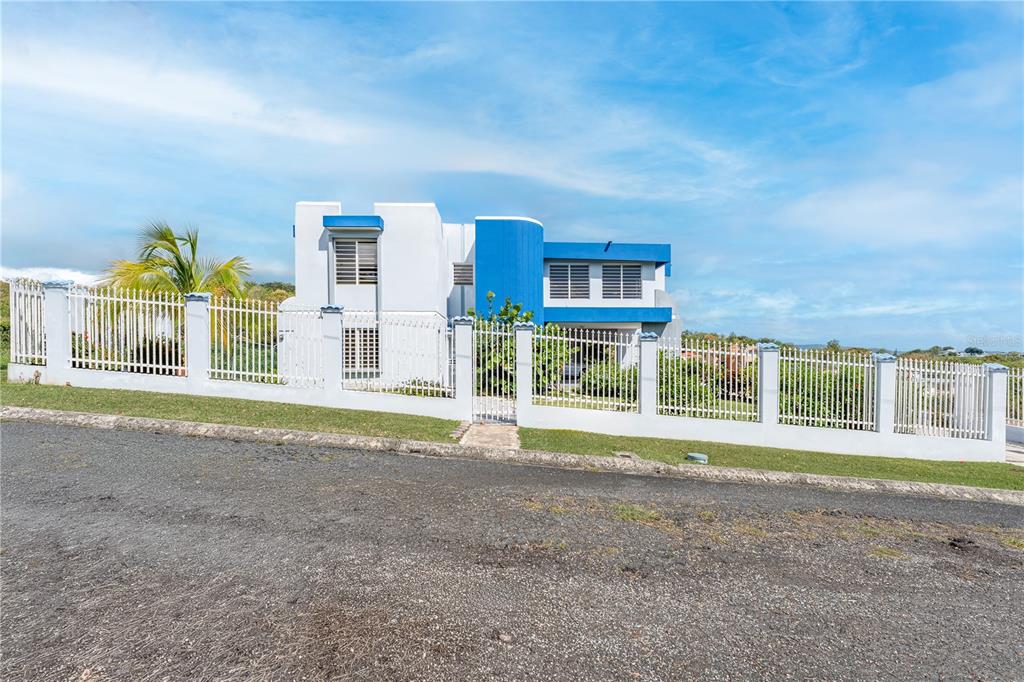 A two-story house with white and blue exterior walls is enclosed by a white fence — SR 307 KM 7.0 VISTAMAR ST ESTANCIAS DE ALTA VISTA, BOQUERON, PR