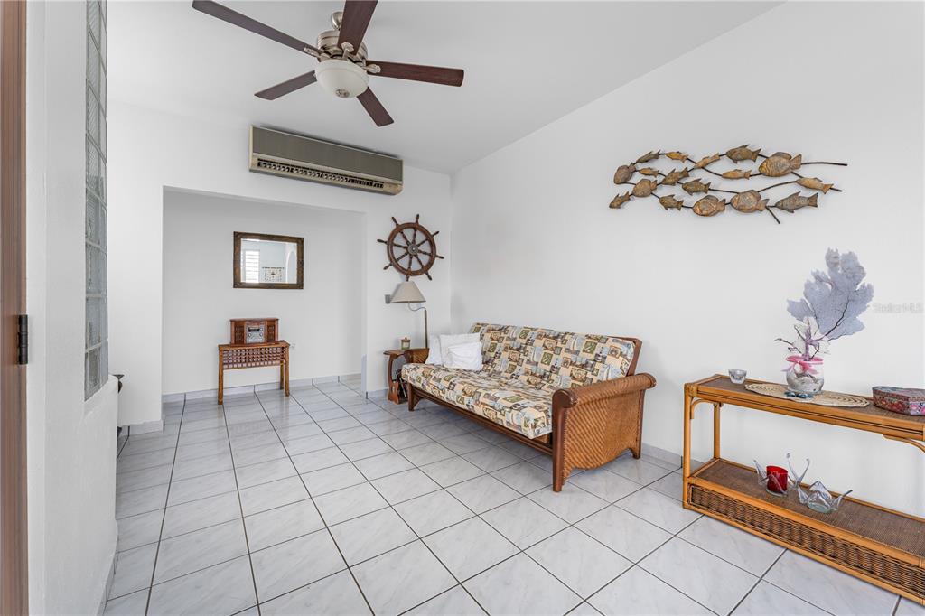 A living room features white tile floors, a rattan sofa, and nautical wall decor — SR 307 KM 7.0 VISTAMAR ST ESTANCIAS DE ALTA VISTA, BOQUERON, PR