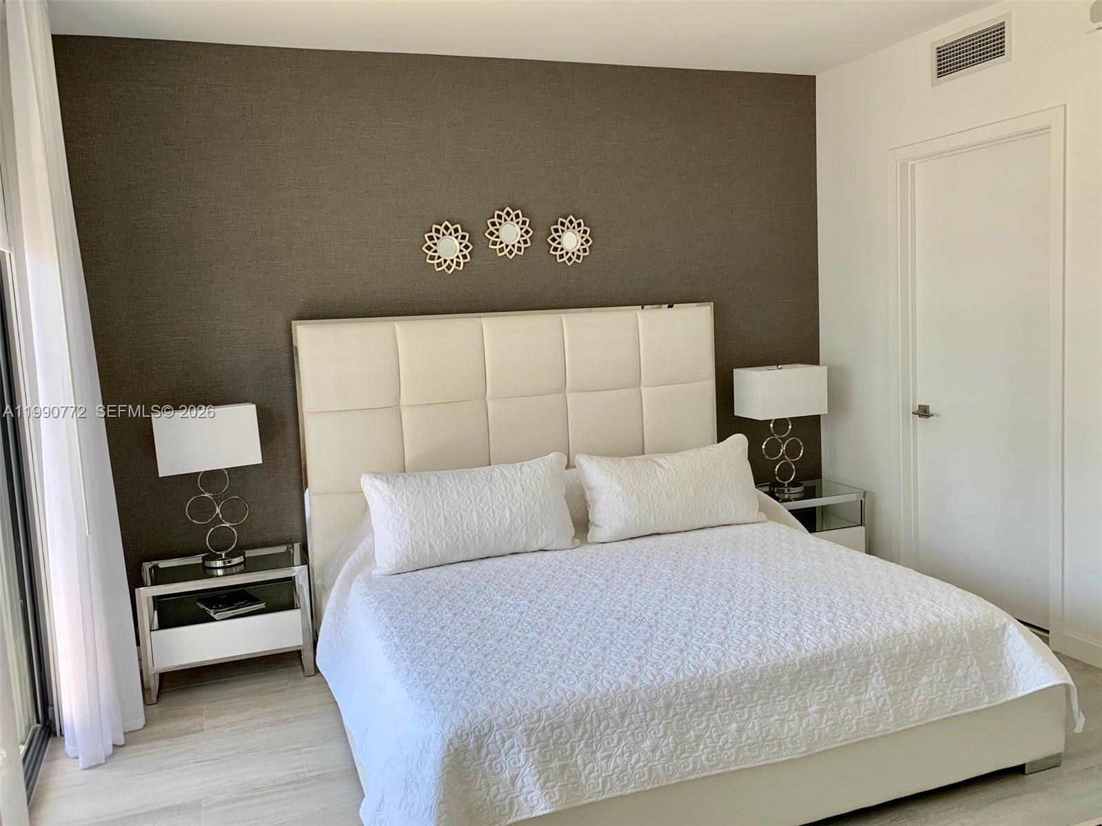 A bedroom features a white tufted headboard against a dark textured accent wall — 55 SW 9 St # 2003, Miami FL 33130, MIAMI, FL