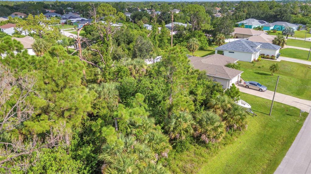 An aerial view of a vacant, wooded lot situated between two suburban residential houses — HIGHTOWER ROAD, NORTH PORT, FL