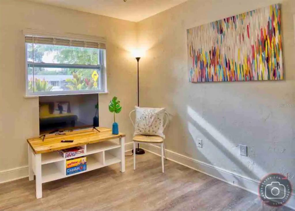 A room features a television on a wooden stand, a chair, and abstract wall art — 4929 BROOKMEADE DRIVE, SARASOTA, FL