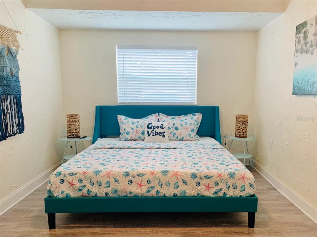 A bedroom features a teal upholstered bed frame, a coastal-themed comforter, and two side tables — 4929 BROOKMEADE DRIVE, SARASOTA, FL