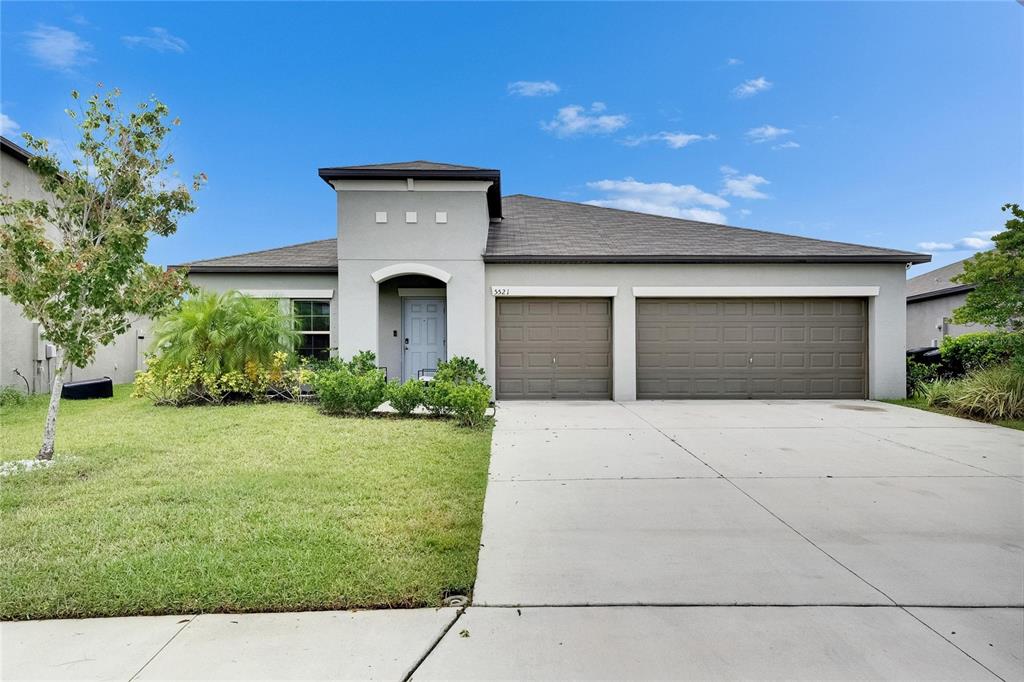 A single-story house with a gray stucco exterior, two garage doors, and a front lawn — 5521 OLANO STREET, PALMETTO, FL