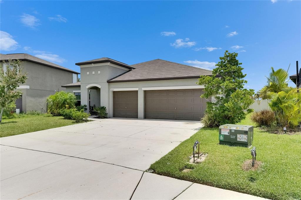 A single-story house with a three-car garage, a concrete driveway, and a green utility box — 5521 OLANO STREET, PALMETTO, FL