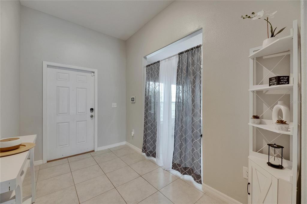 An entryway with tiled floors, a white front door, and a white corner shelving unit — 5521 OLANO STREET, PALMETTO, FL