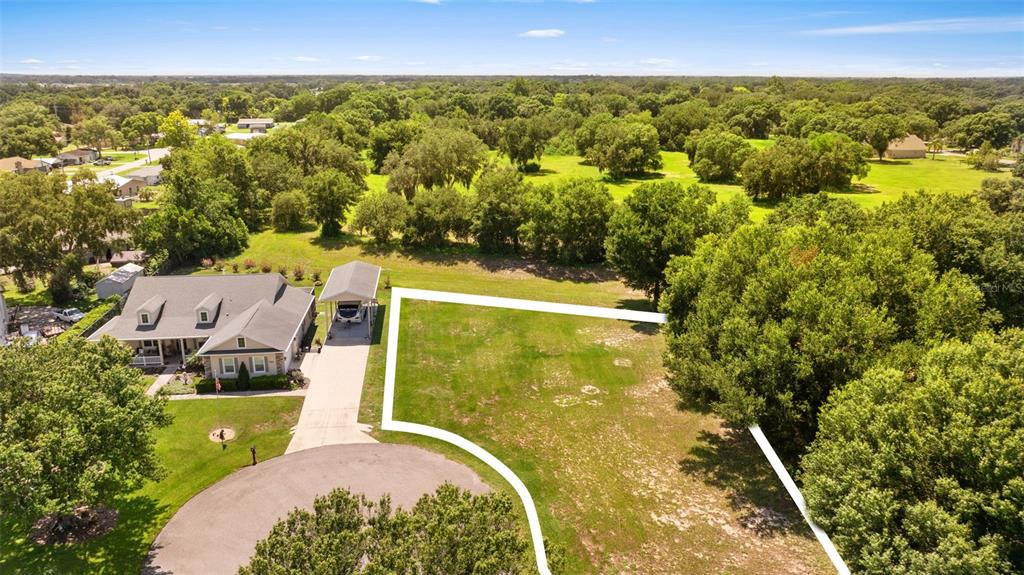 An aerial view shows a house with a carport next to a large vacant lot — 109 BAYBERRY DRIVE, POLK CITY, FL