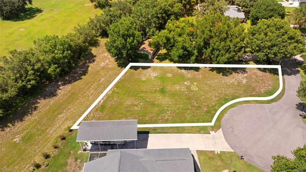 An aerial view shows an empty residential lot outlined in white next to a house — 109 BAYBERRY DRIVE, POLK CITY, FL