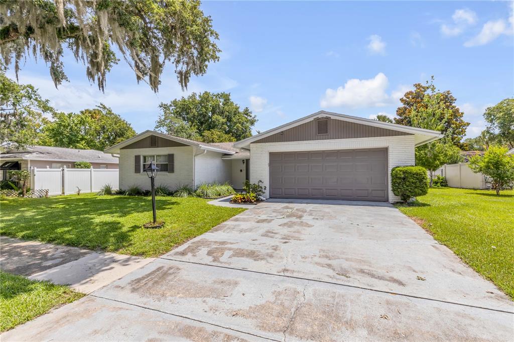 A single-story house with a white brick exterior, a gray garage door, and a concrete driveway — 3655 DAME STREET, PORT ORANGE, FL