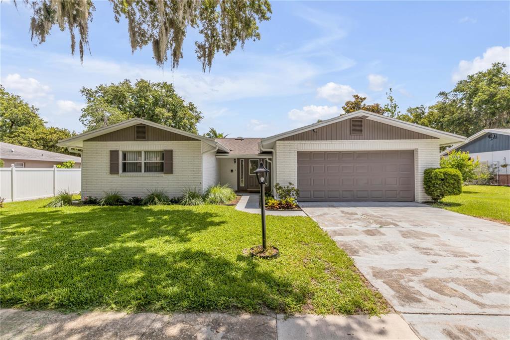 A single-story house with a white brick exterior, brown garage door, and a grassy lawn — 3655 DAME STREET, PORT ORANGE, FL