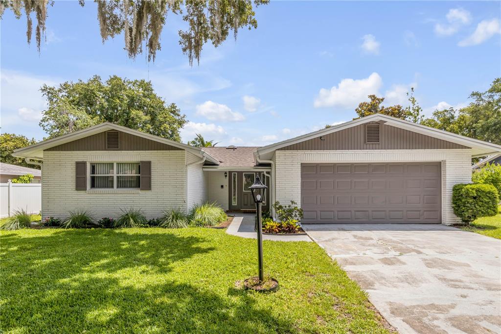A single-story house with white brick, a gray garage door, and a front lawn — 3655 DAME STREET, PORT ORANGE, FL