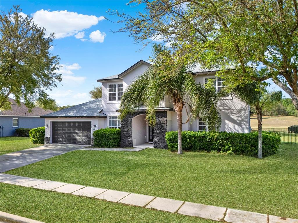 A two-story house with a stone-accented entryway, a garage, and a palm tree in front — 23503 VALDERAMA LANE, SORRENTO, FL
