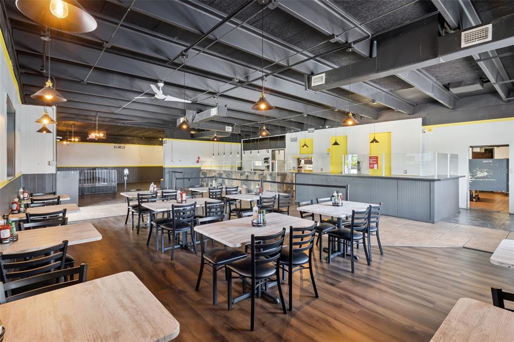 A restaurant dining area features wooden tables, black chairs, and an exposed ceiling with pendant lighting — 518 E MEMORIAL BOULEVARD, LAKELAND, FL