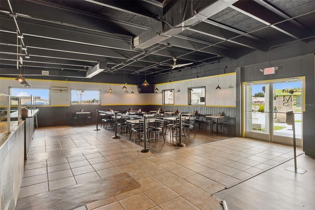 A restaurant dining area features tiled floors, dark exposed ceilings, and multiple tables and chairs — 518 E MEMORIAL BOULEVARD, LAKELAND, FL