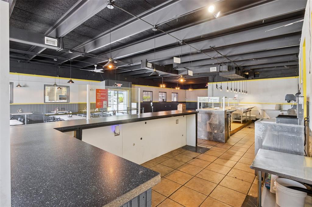An interior view of a commercial kitchen and service counter with exposed black ceiling beams — 518 E MEMORIAL BOULEVARD, LAKELAND, FL