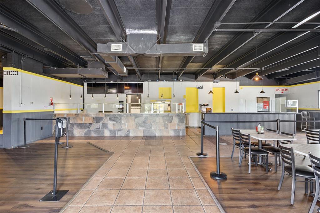 A restaurant interior features a stone service counter, tile and wood flooring, and exposed ceilings — 518 E MEMORIAL BOULEVARD, LAKELAND, FL