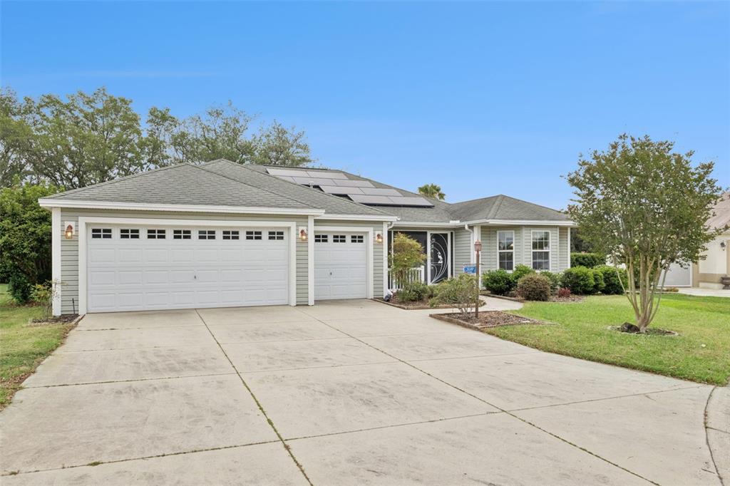A single-story house with light green siding, a two-car garage, and rooftop solar panels — 2039 TYNTE TERRACE, THE VILLAGES, FL
