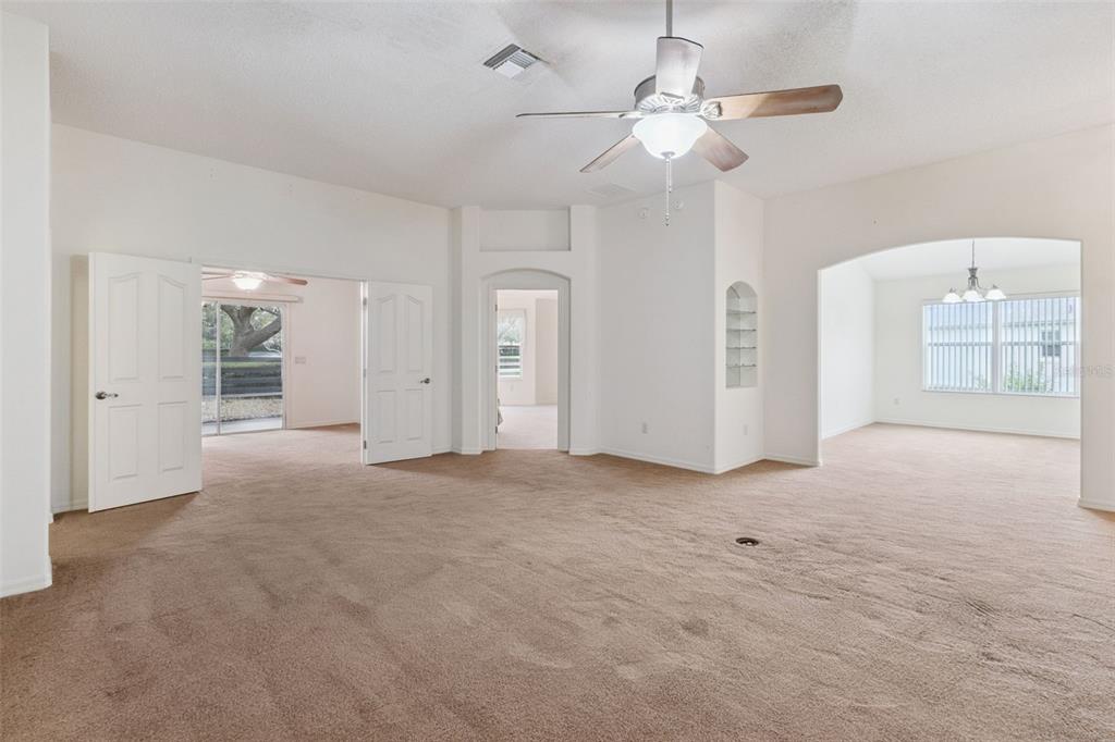 A spacious room with beige carpeting, white walls, a ceiling fan, and multiple arched doorways — 2039 TYNTE TERRACE, THE VILLAGES, FL