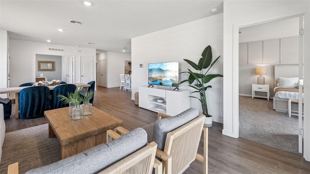 A living room with a television, two armchairs, and an adjacent bedroom with carpeted flooring — 2508 KINSALE LANE, ORMOND BEACH, FL