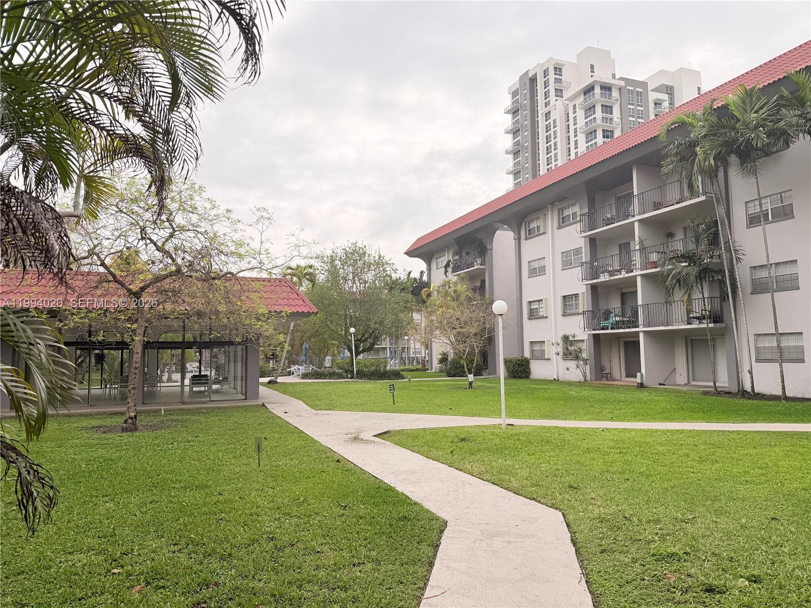 A concrete path winds through a grassy courtyard between a low building and apartments — 8101 SW 72nd Ave # 403W, Miami FL 33143, MIAMI, FL