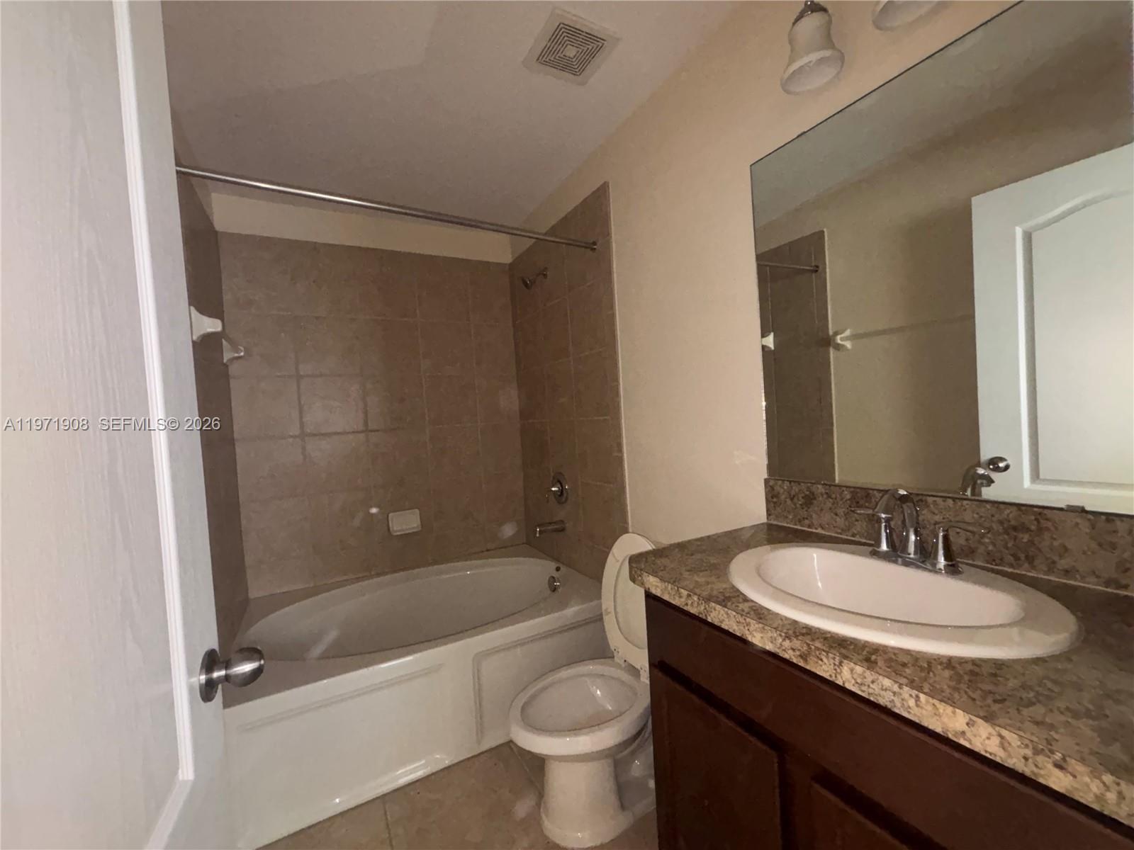 A bathroom features a tiled tub-shower combination, a toilet, and a vanity with a mirror — 330 Carina Cir, Sanford FL 32773, SANFORD, FL