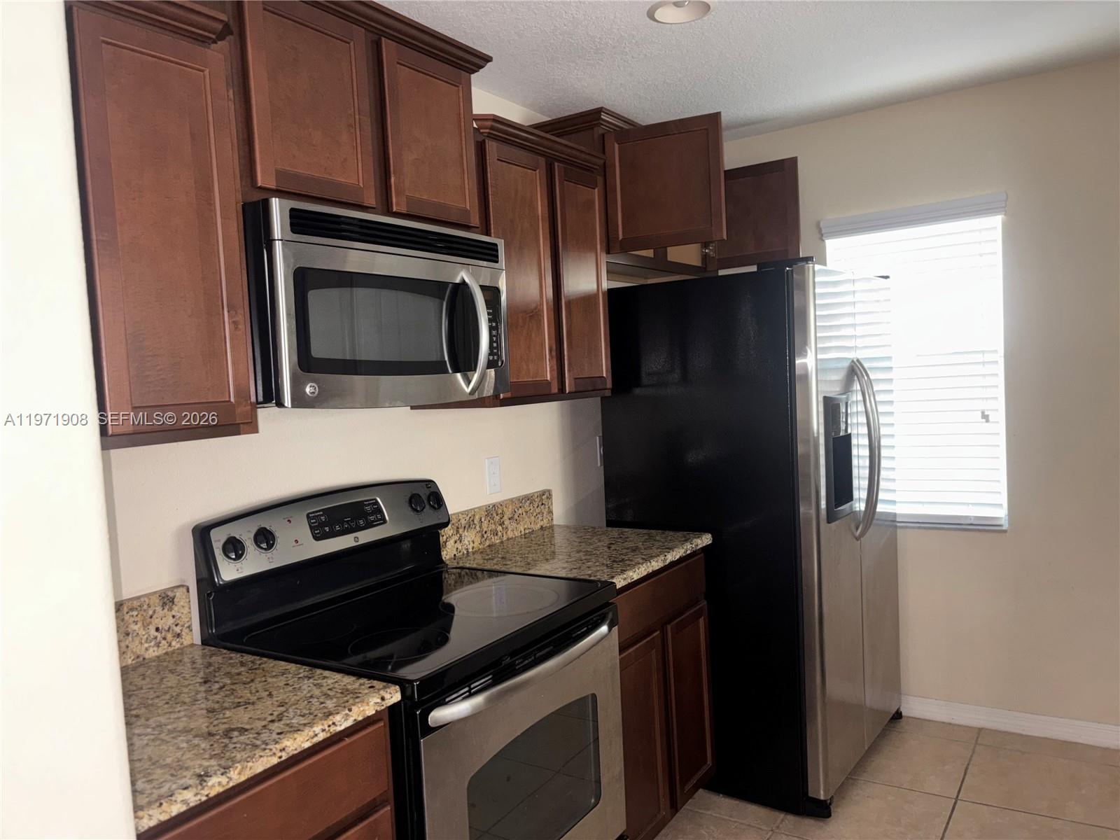 A kitchen features dark wood cabinets, granite countertops, and stainless steel appliances — 330 Carina Cir, Sanford FL 32773, SANFORD, FL