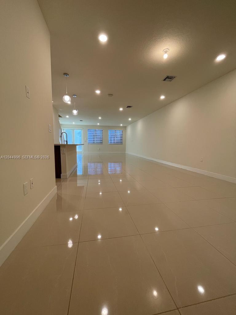 An open-concept living area features light-colored tile flooring, recessed lighting, and a kitchen island — 10317 NW 66th St # 10317, Doral FL 33178, DORAL, FL
