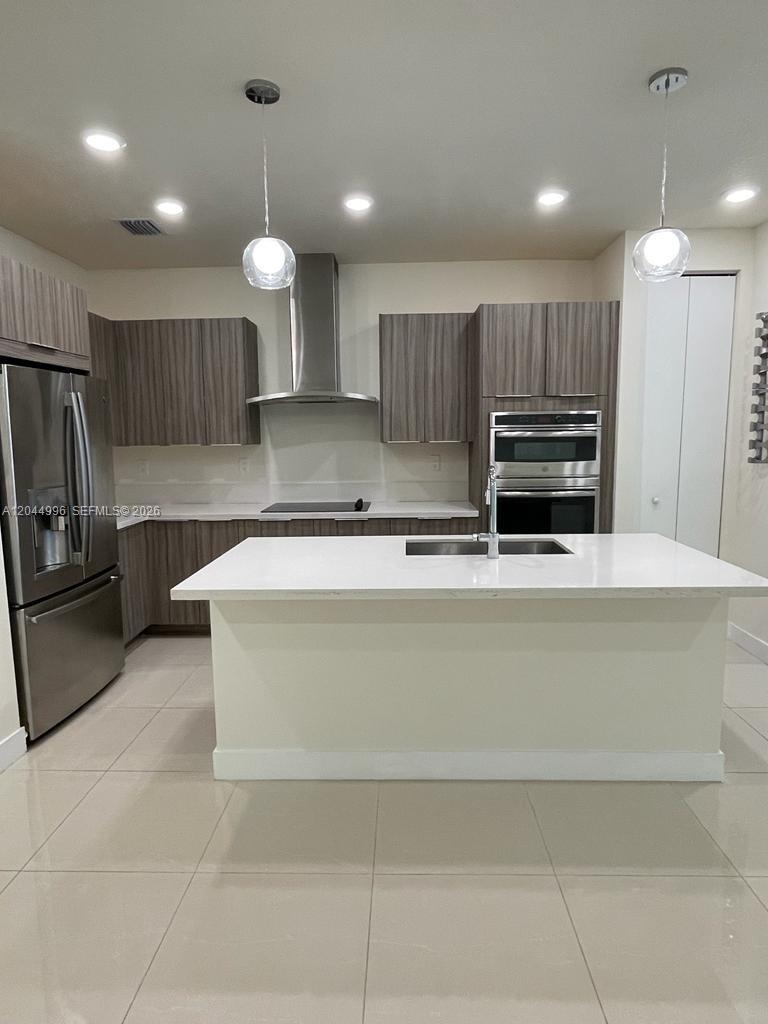 A modern kitchen features wood-grain cabinets, stainless steel appliances, and a white quartz island — 10317 NW 66th St # 10317, Doral FL 33178, DORAL, FL
