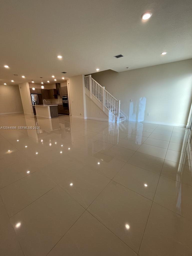An open-concept living area features large light-colored floor tiles, recessed lighting, and a staircase — 10317 NW 66th St # 10317, Doral FL 33178, DORAL, FL