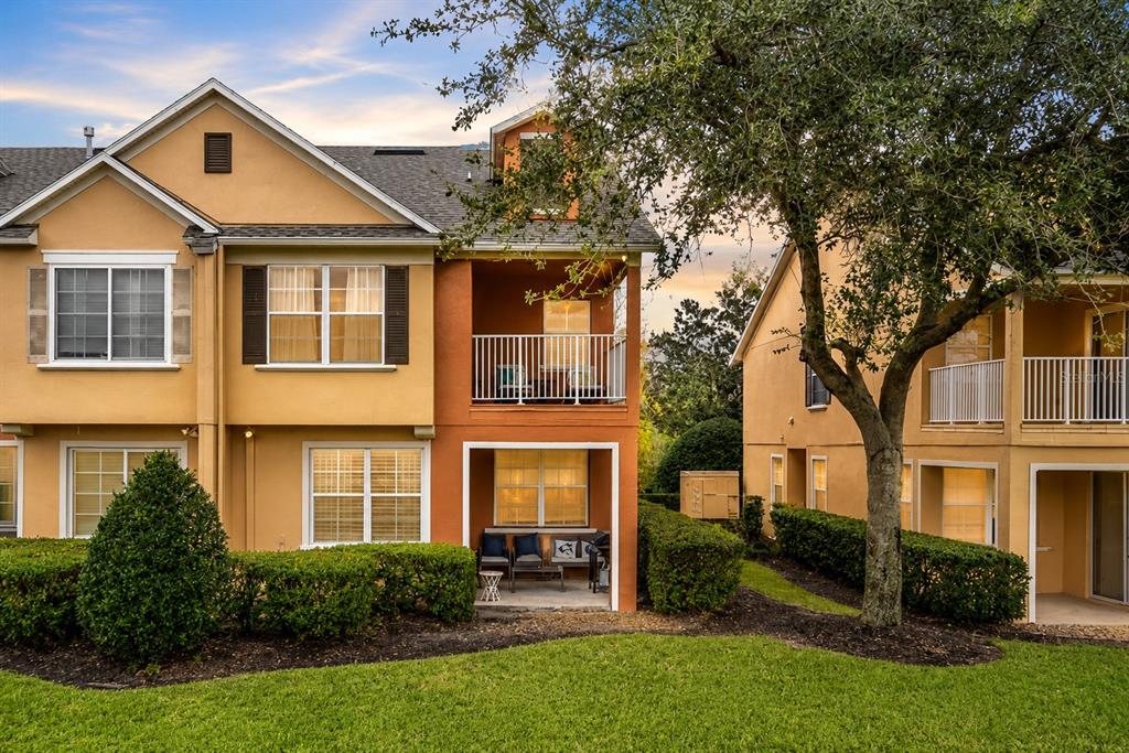 The exterior of a multi-story tan townhouse features a ground-level patio and a second-floor balcony — 894 ASSEMBLY COURT, REUNION, FL